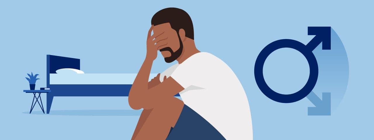 A man sitting by a bed with his head in his hand