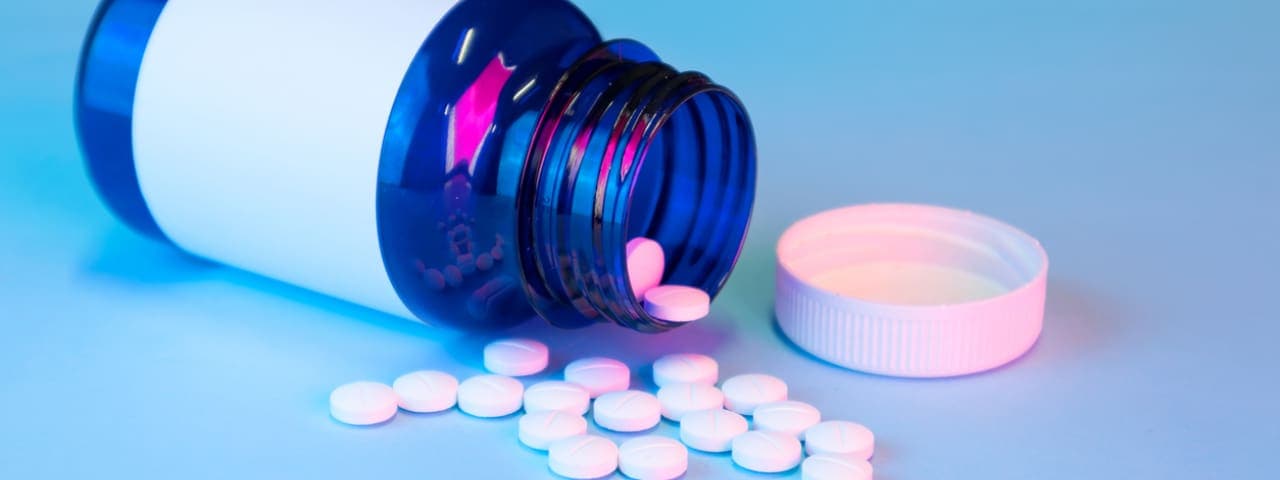 A pill bottle on its side, with pills spilling out