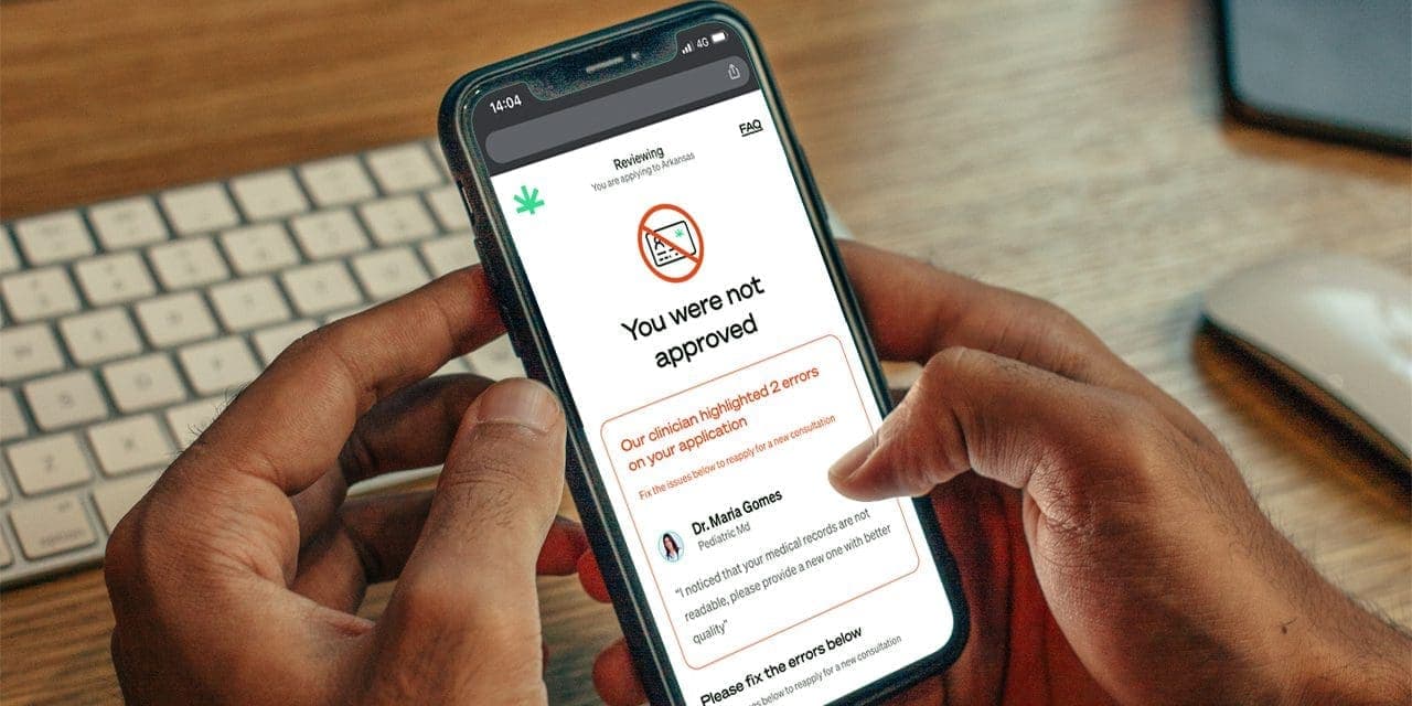closeup of hands holding a cellphone showing a rejection from applying for marijuana card